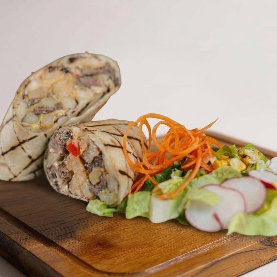 Two grilled burritos with a side salad of lettuce, radishes, and shredded carrots on a wooden board.