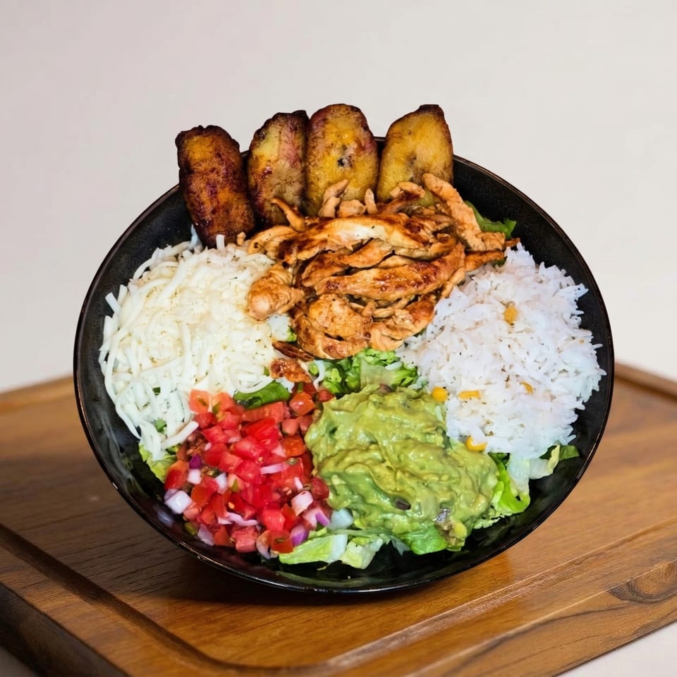 A Casa Encanto Mexican bowl with chicken, rice, guacamole, tomatoes, cheese, and plantains.